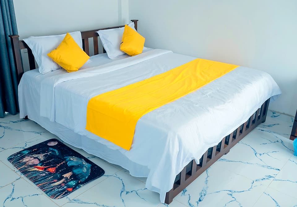 Double bed made up in white linen with a yellow runner