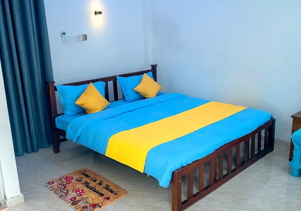 Double bed made up in blue linen with yellow cushions